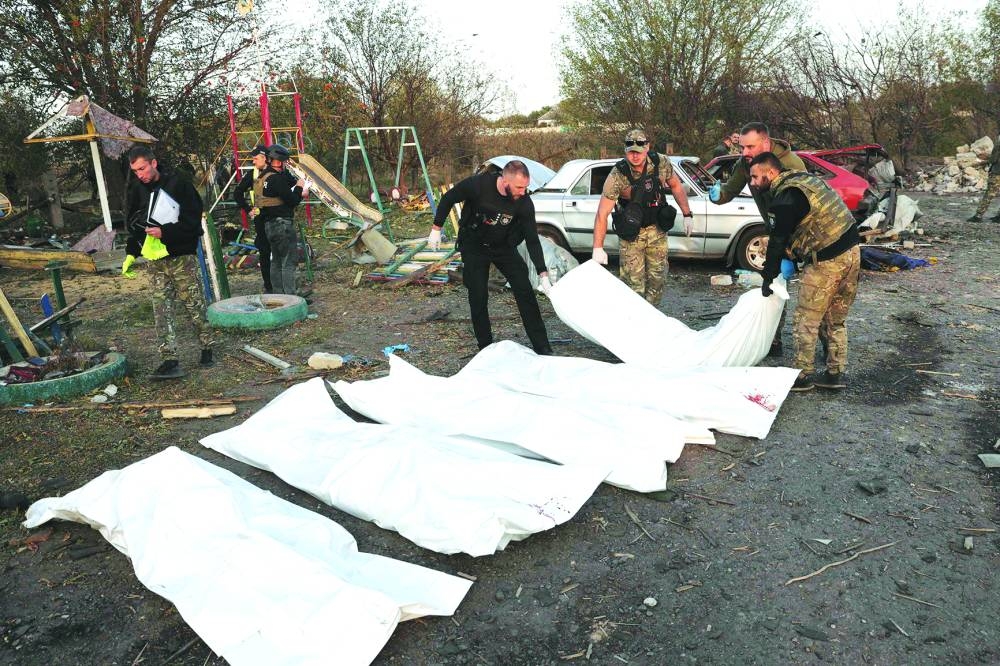 
Police officers carry bodies out of a destroyed shop and cafe after a Russian strike in the village of Groza, eastern Ukraine. 