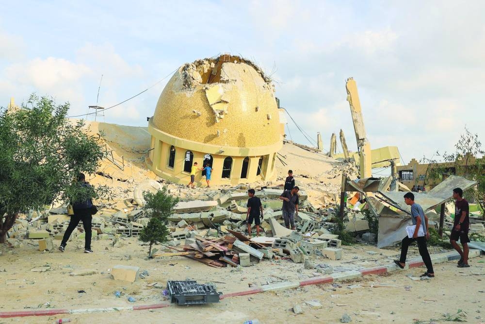 
Mourners react during the funeral of Palestinian twin babies Ossayd and Mohamed Abu Hmaid, their mother and their three sisters, who health officials said were killed in Israeli strikes, during their funeral in Khan Yunis in the southern Gaza Strip, yesterday. Right: A man and children walk on the ruins of a mosque destroyed in Israeli airstrikes in Khan Yunis. 
