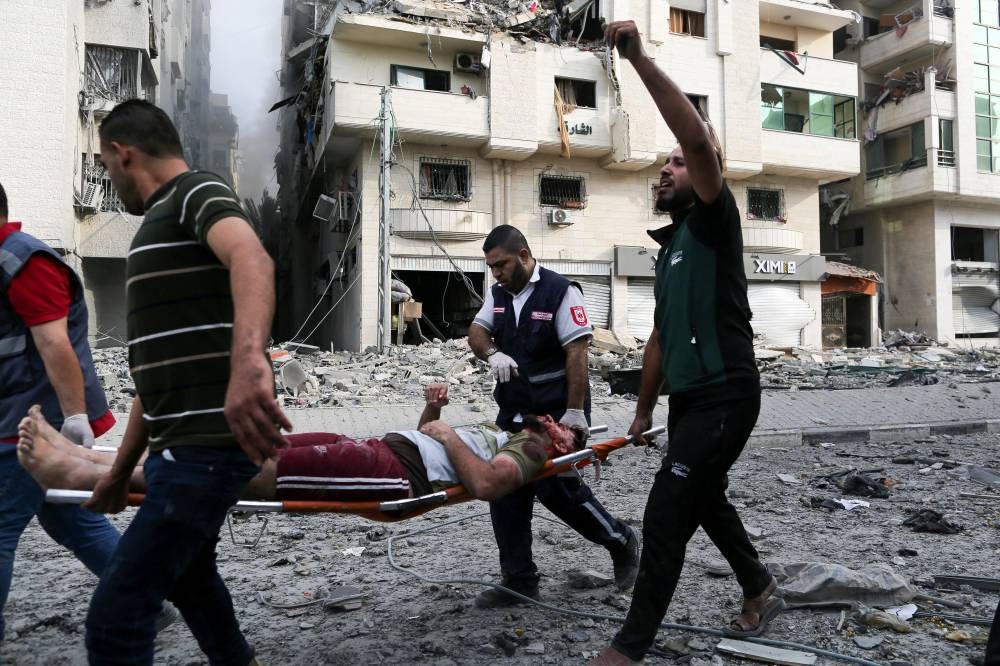 Palestinians carry a wounded man on a stretcher following Israeli strikes on a residential building, in Gaza City, Monday. REUTERS