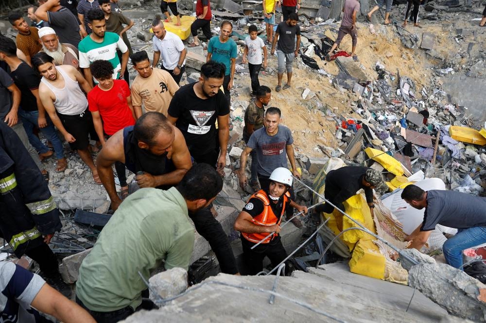 Palestinians gather next to the rubble of a building destroyed in Israeli strikes, in the southern Gaza Strip Monday. REUTERS