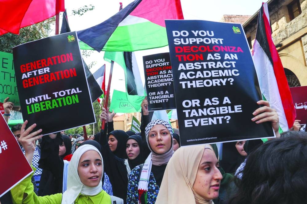 Students from the American University of Beirut (AUB) lift placards during a rally in support of Palestinians outside the main gate of the university in the Lebanese capital, on Monday.