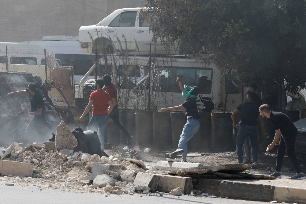 People throw objects as Palestinians take part in a protest following Israeli strikes on Gaza, in Nablus, in the Israeli-occupied West Bank, Friday. REUTERS