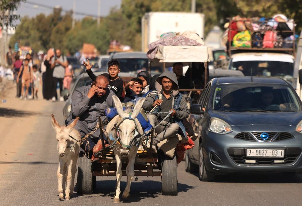  Riding a donkey drawn cart as family along with hundreds of other Palestinian carrying their belongings flee following the Israeli army's warning to leave their homes and move south before an expected ground offensive, in Gaza City  Friday. AFP