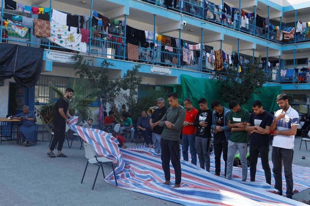 Palestinians, who fled their houses amid Israeli strikes, pray as they shelter at a United Nations-run school, after Israel's call for more than 1 million civilians in northern Gaza to move south, in Khan Younis in the southern Gaza Strip, Saturday. REUTERS