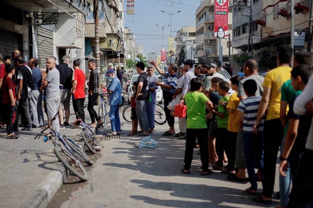 Palestinians wait to buy bread outside a bakery, amid the ongoing conflict between Israel and Palestinian Islamist group Hamas, in Khan Younis in the southern Gaza Strip Saturday. REUTERS