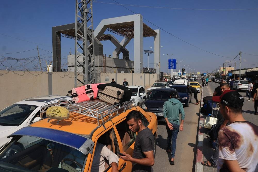 Palestinians with foreign passports arrive at the Rafah gate hoping to cross into Egypt as Israel's attacks on the Gaza Strip continues on Saturday. AFP