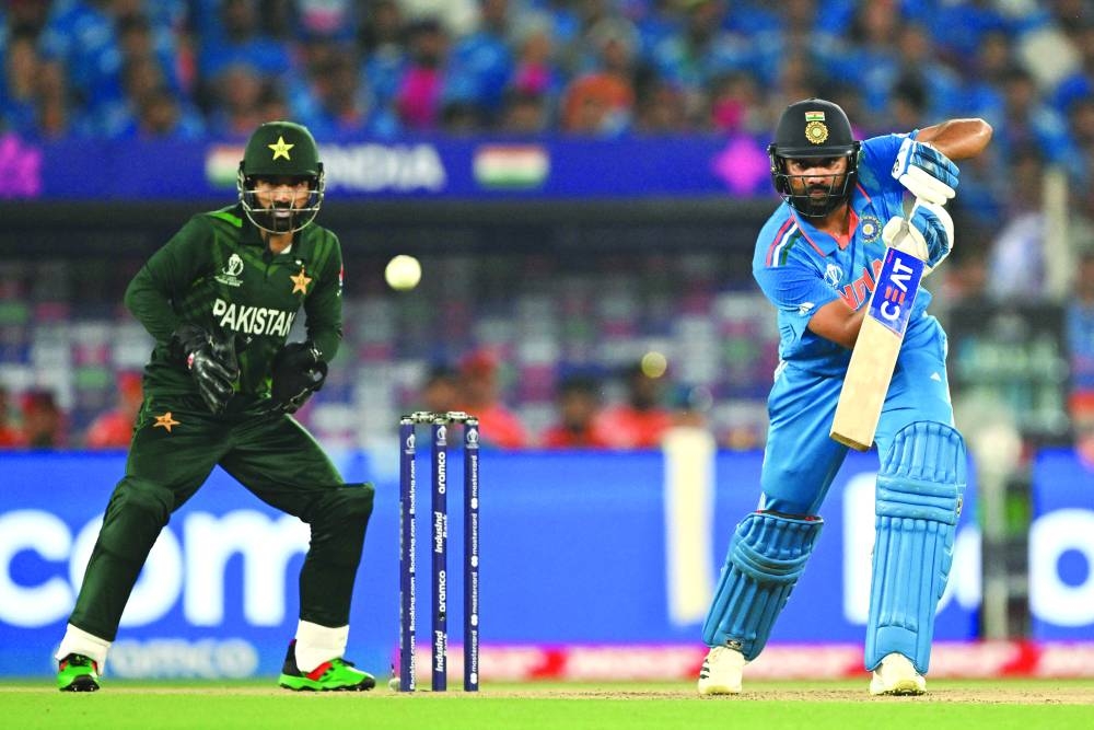 India’s captain Rohit Sharma (right) plays a shot as Pakistan’s wicketkeeper Mohammad Rizwan watches during the 2023 ICC Men’s Cricket World Cup one-day international match between India and Pakistan on Saturday. (AFP)