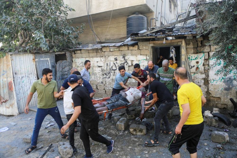 Palestinians carry a casualty following Israeli strikes in Gaza City Sunday. REUTERS