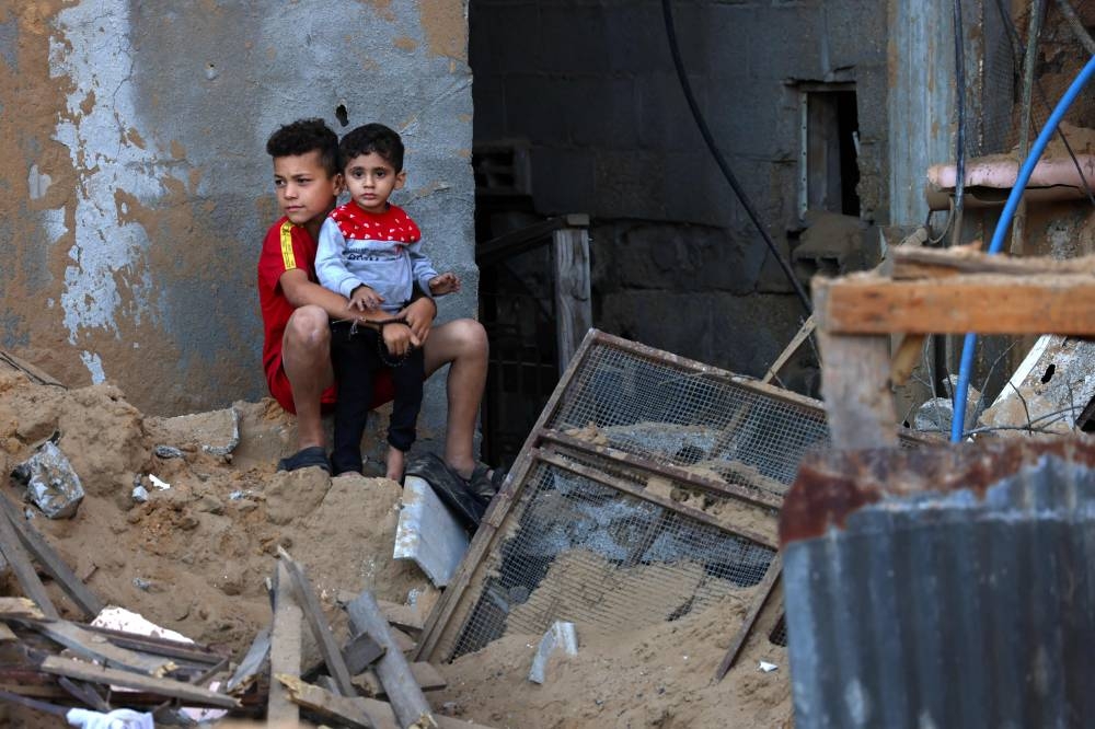 Palestinian boys look at the damage after an Israeli military strike on the Rafah refugee camp, in the southern of Gaza Strip Sunday. AFP