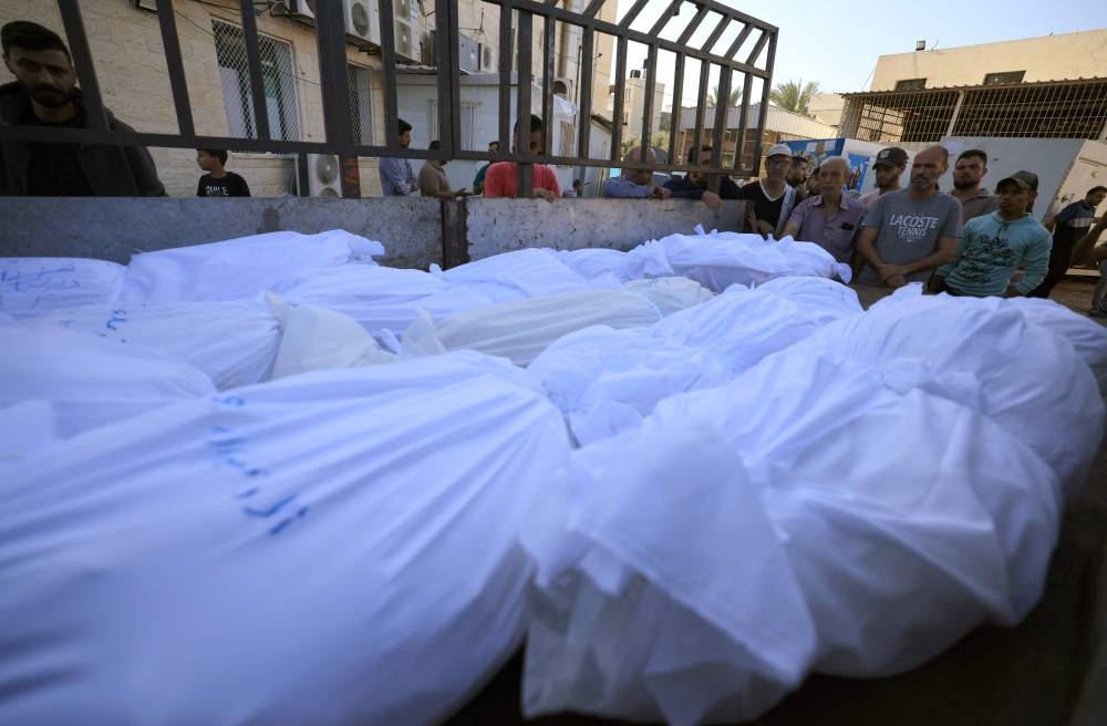 A lorry carries bodies wrapped in burial shrouds of the Abu al-Awf family, displaced from northern Gaza and killed in a home housing internally displaced Palestinians, as they are taken for burial from the Al-Aqsa hospital in the town of Deir Al-Balah, in the central Gaza Strip,  Sunday. AFP