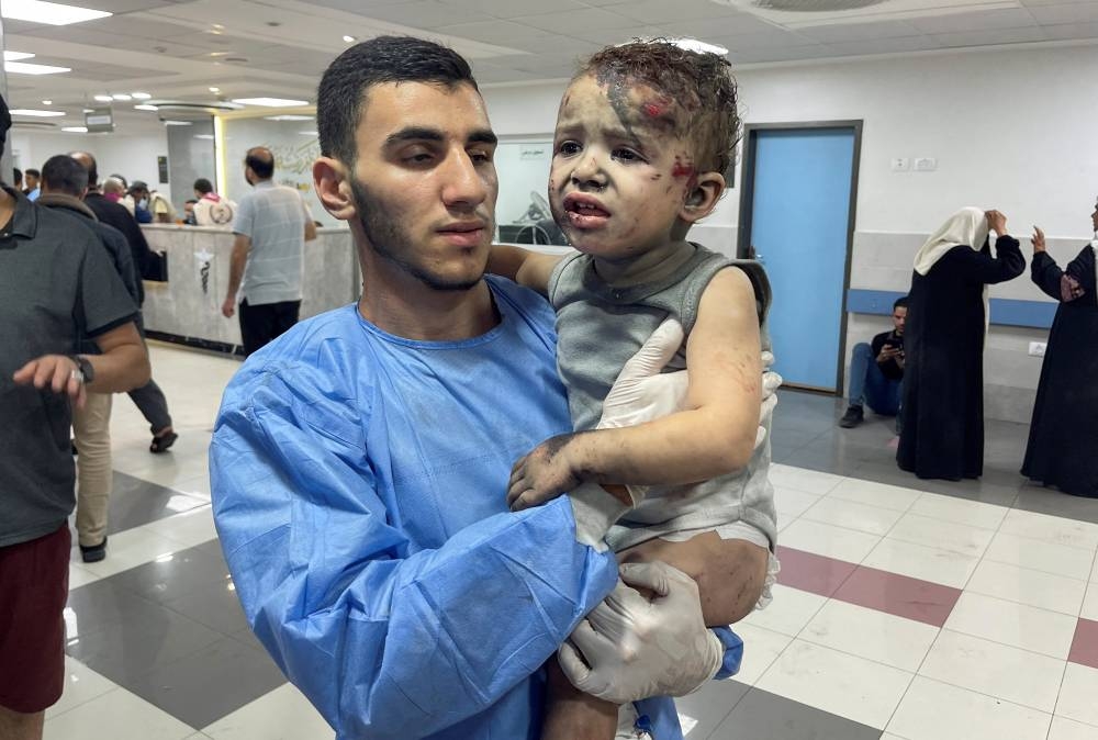 A medic carries a Palestinian boy, who was wounded in an Israeli strike, at Shift hospital in Gaza City, Sunday. REUTERS