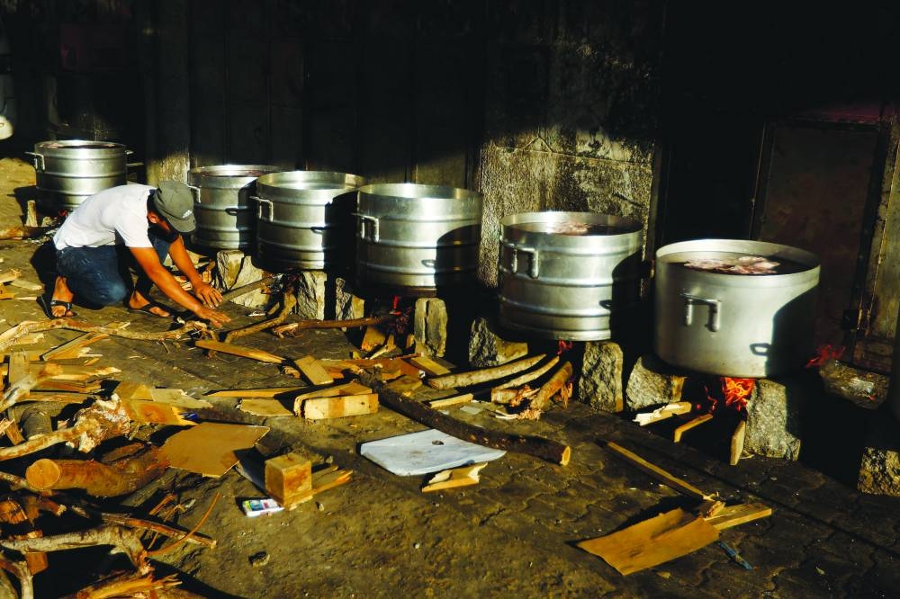 People cook on firewood amid shortages of fuel and gas to provide food for Palestinians who fled their houses amid Israeli strikes in Khan Yunis, in the southern Gaza Strip, Sunday.