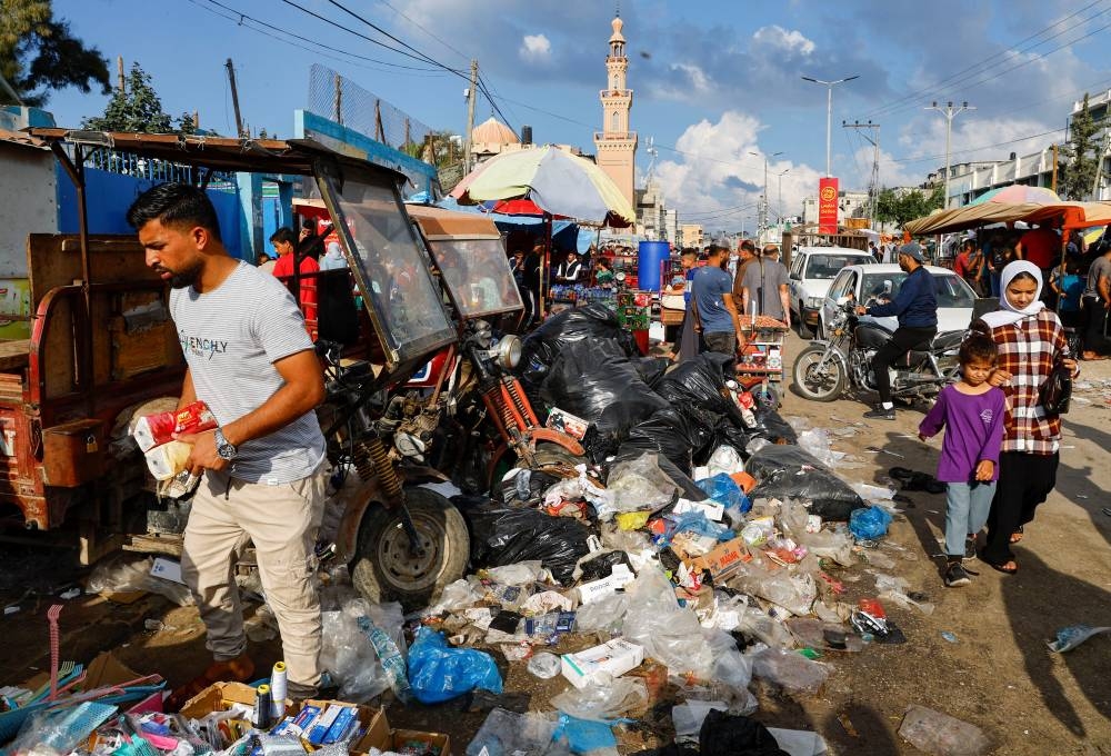 Palestinians walk past piles of garbage that threaten to spark an environmental catastrophe, amid the ongoing Israeli-Palestinian conflict, in Khan Younis in the southern Gaza Strip, Monday. REUTERS