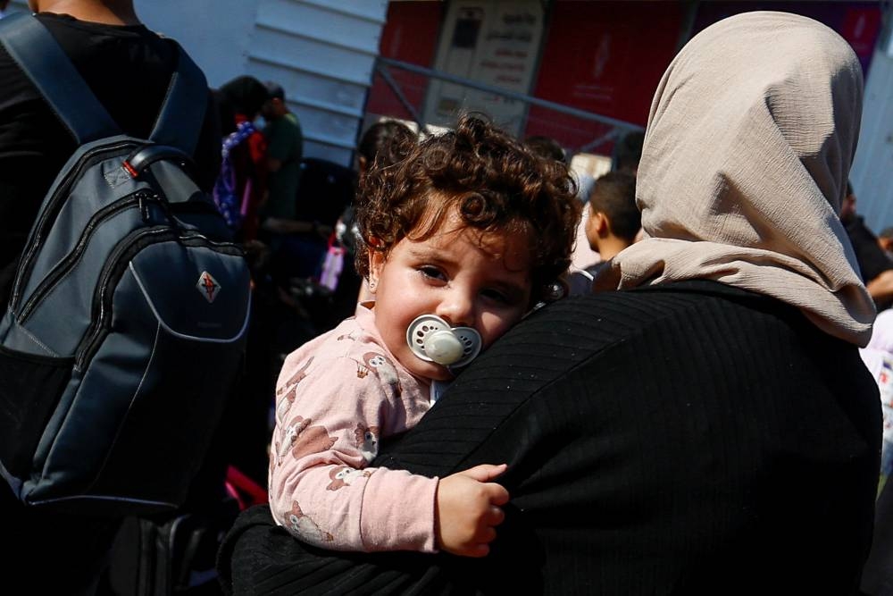 Palestinians with dual citizenship gather outside Rafah border crossing with Egypt in the hope of getting permission to leave Gaza, amid the ongoing Israeli-Palestinian conflict, in Rafah in the southern Gaza Strip Monday. REUTERS