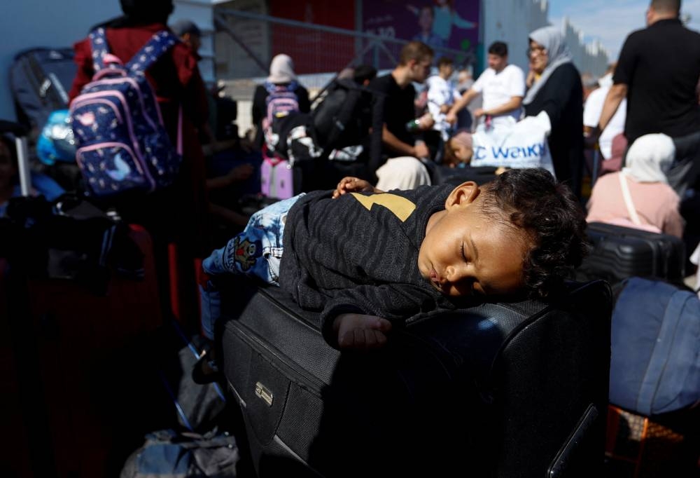 A child sleeps as Palestinians with dual citizenship gather outside Rafah border crossing with Egypt in the hope of getting permission to leave Gaza, amid the ongoing Israeli-Palestinian conflict, in Rafah in the southern Gaza Strip Monday. REUTERS
