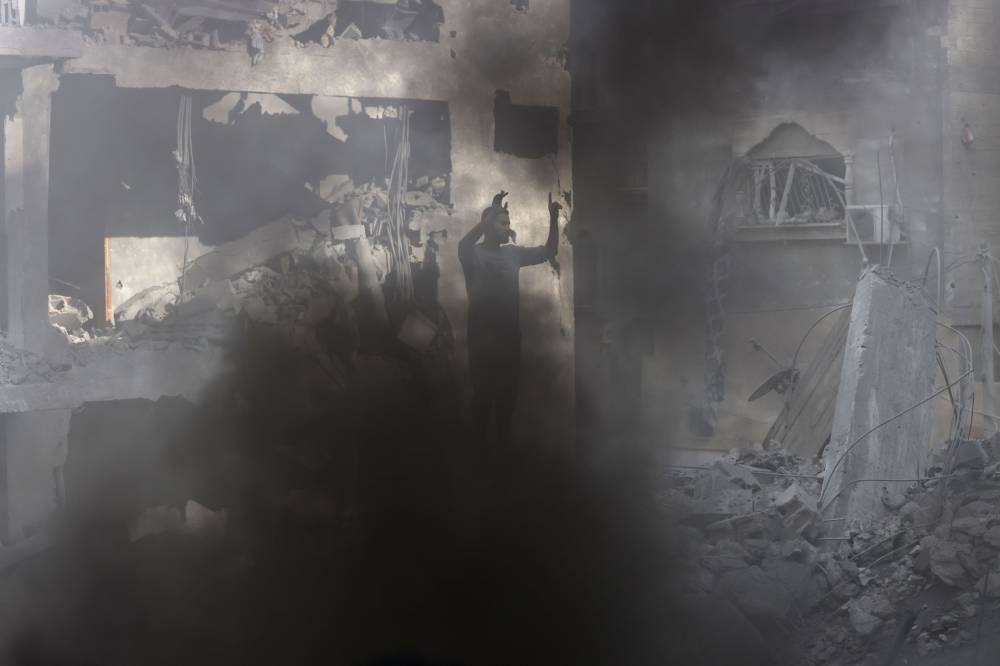 A Palestinian reacts as smoke billows after an Israeli airstrike at the Rafah refugee camp, in the southern Gaza Strip Tuesday. AFP