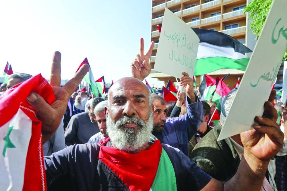 
Syrians wave the Palestinian flag during a gathering in Damascus, yesterday, to express their solidarity with the Gaza Strip. 