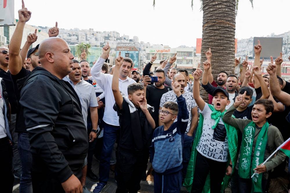 Palestinians take part in a protest in support of the people in Gaza, after hundreds of Palestinians were killed in a blast at Al-Ahli hospital in Gaza that Israeli and Palestinian officials blamed on each other, in Nablus in the Israeli-occupied West Bank Wednesday. REUTERS
