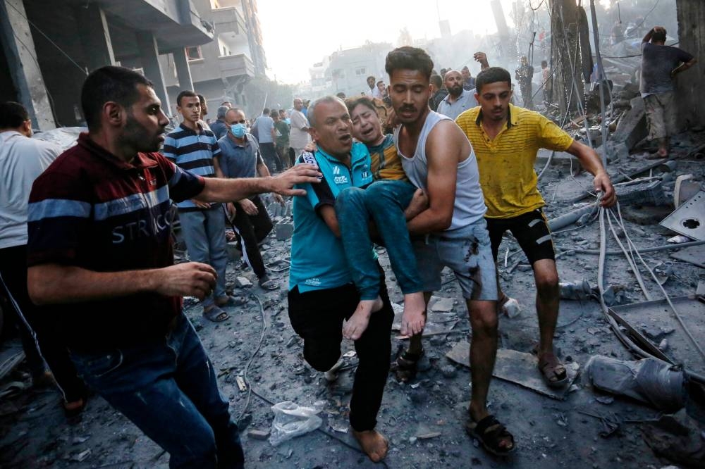 Men carry away an injured girl following an Israeli strike on the town of Deir Al-Balah in the central Gaza Strip on Wednesday. AFP