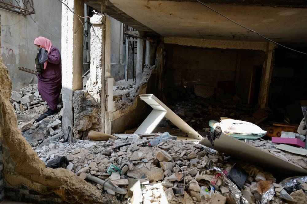 A Palestinian woman walks at the site of a damaged building following an Israeli raid in Tulkarm in the Israeli-occupied West Bank Friday. REUTERS