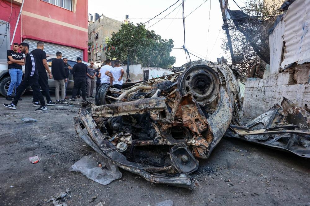 Palestinians stand next to a car destroyed during a raid by Israeli troops at the Nur Shams refugee camp near the northern city of Tulkarm in the occupied West Bank Friday. AFP