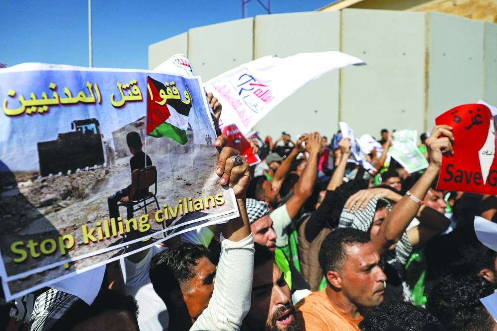 Demonstrators hold placards denouncing the killing of civilians at a protest by the Rafah border crossing with the Gaza Strip on the Egyptian side in the east of North Sinai province, on Friday during the visit of the UN secretary-general to oversee preparations for the delivery of humanitarian aid.