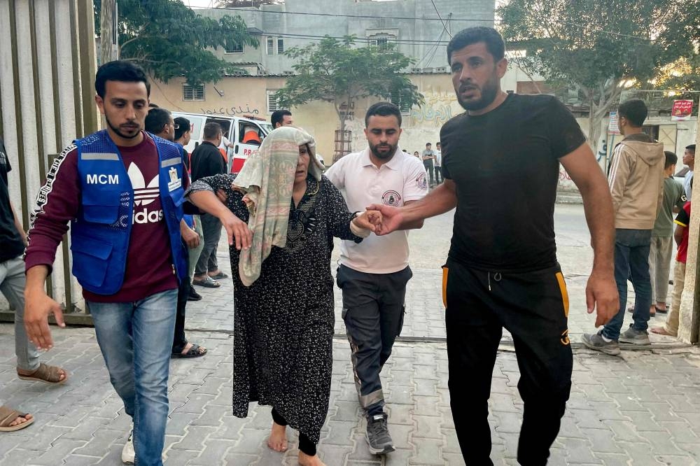 Men assist an injured elderly woman arriving for treatment after Israeli bombardment, at the Kuwaiti hospital in Rafah in the southern Gaza Strip on Saturday. AFP