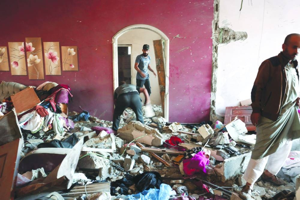 
People sift through the rubble inside a house damaged in an Israeli bombardment in Rafah in the southern Gaza Strip, yesterday. 