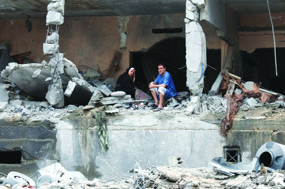 
Palestinians sit among the rubble of a damaged residential building, in the aftermath of Israeli strikes, in Gaza City, on October 10, 2023. 