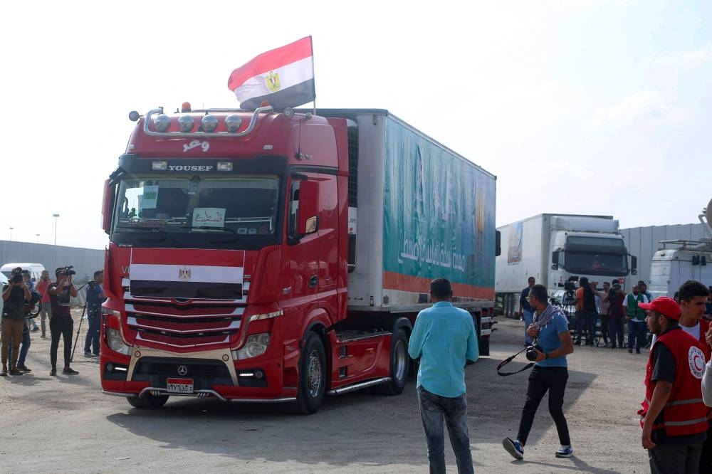 People on the Egyptian side of the Rafah border crossing watch as a convoy of lorries carrying humanitarian aid crosses to the Gaza Strip on Sunday. AFP
