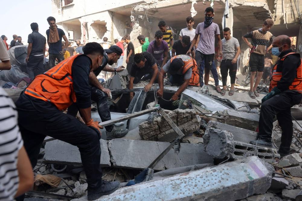 Rescuers search for victims or survivors in a car covered by the rubble of a house destroyed in an Israeli strike on Rafah in the southern Gaza Strip on Sunday. AFP