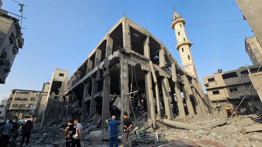 Palestinians gather around the remains of a mosque destroyed in Israeli strikes, Sunday. REUTERS