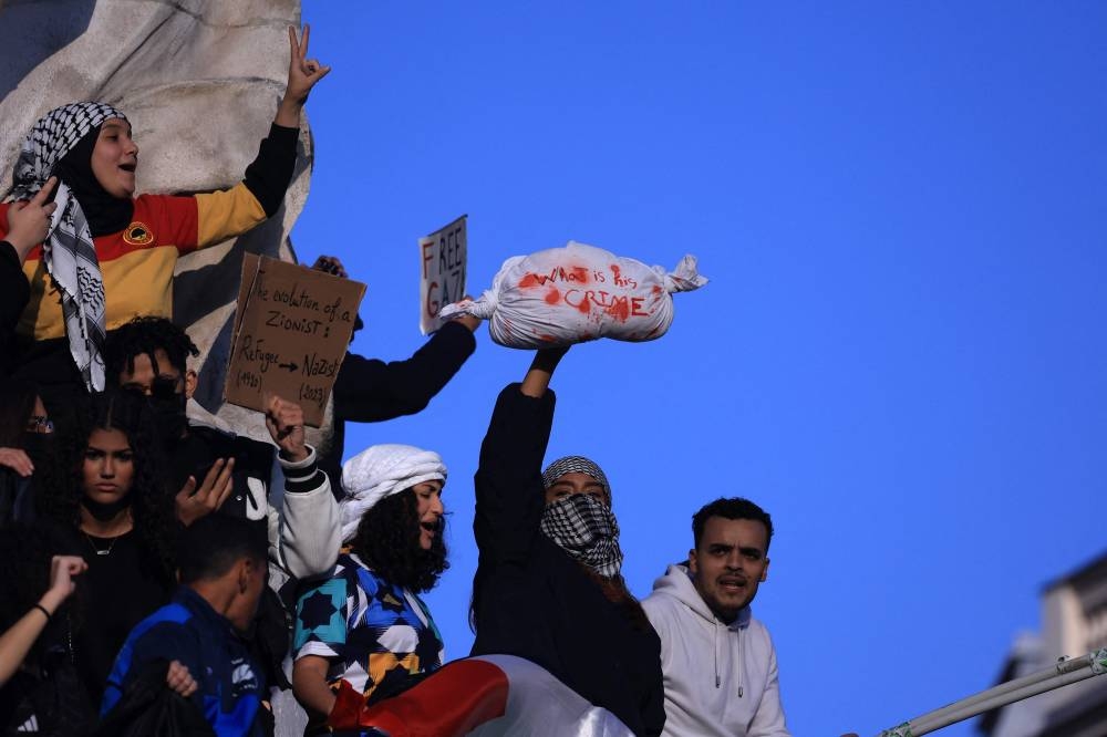 A protestor wearing a keffiyeh shouts slogans during a demonstration calling for peace in Gaza, at Place de la Republique in Paris, Sunday. AFP
