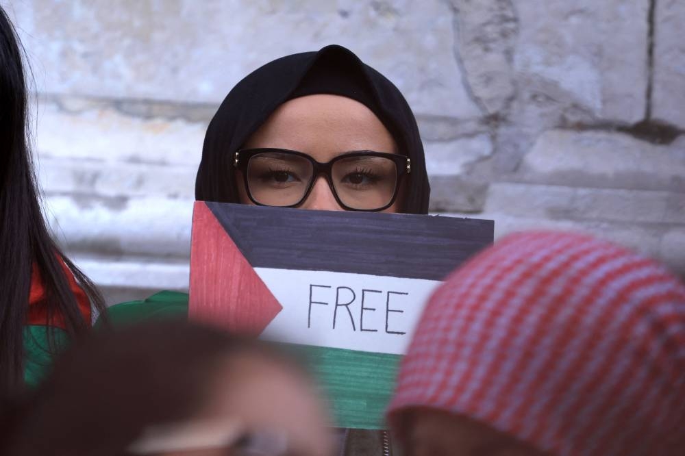A protestor holds a placard of a Palestinian flag with "Free" written on it during a demonstration calling for peace in Gaza at Place de la Republique in Paris, Sunday. AFP