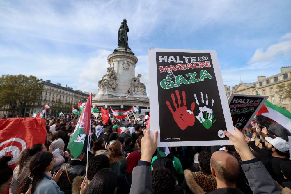 Protestors hold placards and flags as they gather at Place de la Republique for a demonstration calling for peace in Gaza in Paris, Sunday. AFP