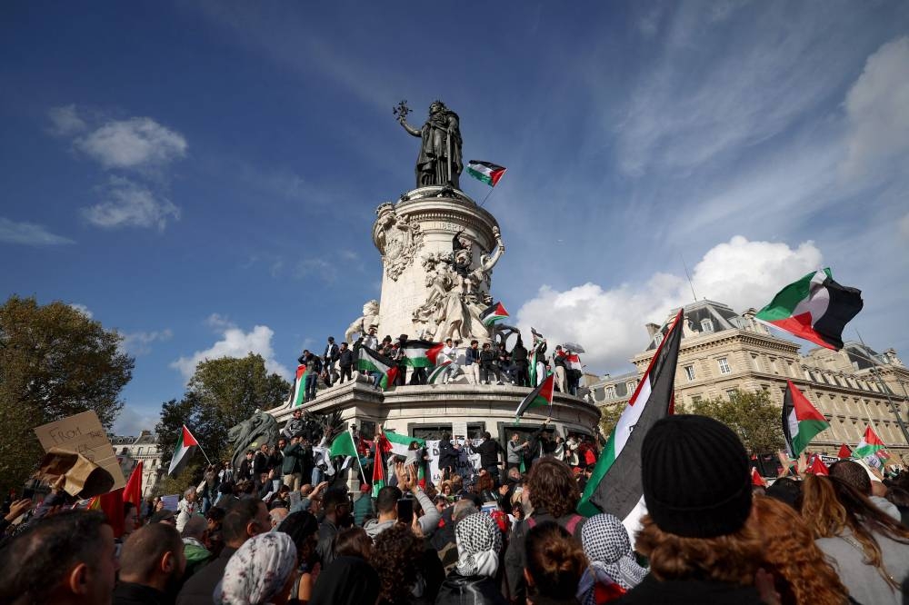 Protestors wave Palestinian flags as they stand on the Monument a la Republique during a demonstration calling for peace in Gaza, at Place de la Republique in Paris, Sunday. AFP