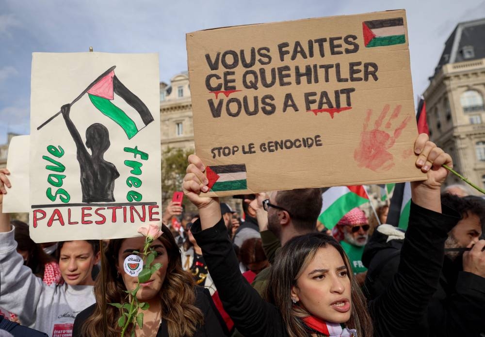 A protestor holds a placard which reads "You do what Hitler did to you" as they gather at Place de la Republique during a demonstration calling for peace in Gaza in Paris, Sunday. AFP