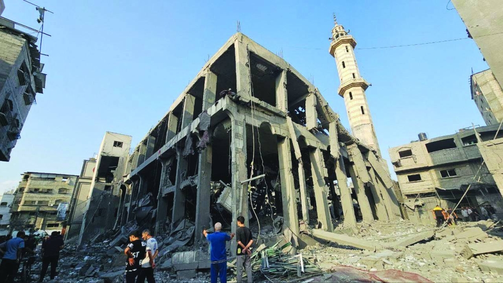 
Palestinians gather around the remains of a mosque destroyed in Israeli strikes, as the conflict continues, in the northern Gaza Strip, yesterday. 