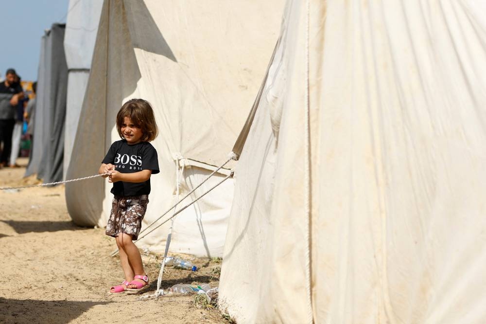 A child walks outside a tent, as Palestinians, who fled their houses amid Israeli strikes, take shelter in a tent camp at a United Nations-run centre, after Israel's call for more than 1 million civilians in northern Gaza to move south, in Khan Younis in the southern Gaza Strip, on Monday. REUTERS