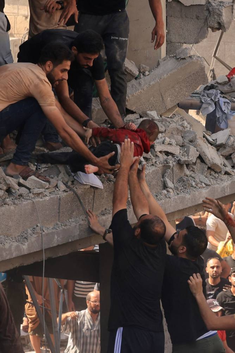 Rescuers pull a child out of the rubble of a building hit in an Israeli air strike in Khan Yunis in the southern Gaza Strip on Tuesday. AFP