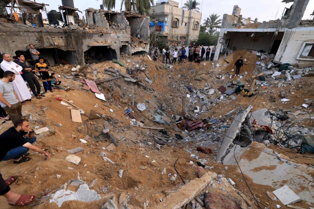 Palestinians stand around a crater caused by an Israeli strike in Khan Yunis in the southern Gaza Strip on Tuesday. AFP