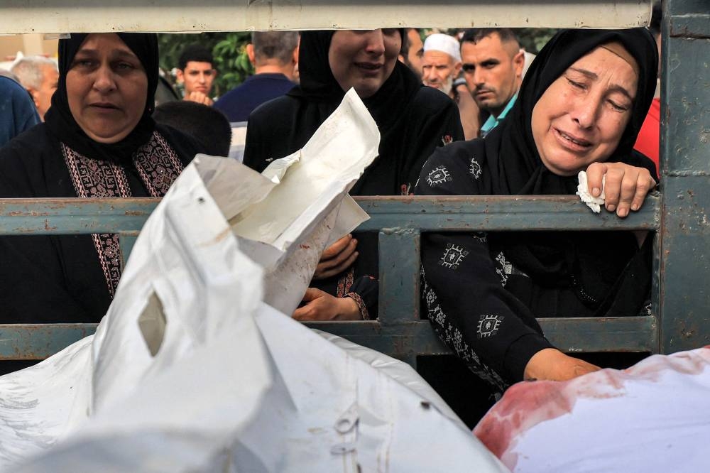 Women react while standing behind a truck carrying the bodies of victims of Palestinians killed during Israeli bombardment, before their funerals outside the morgue at Nasser Hospital in Khan Yunis in the southern Gaza Strip on Wednesday. AFP
