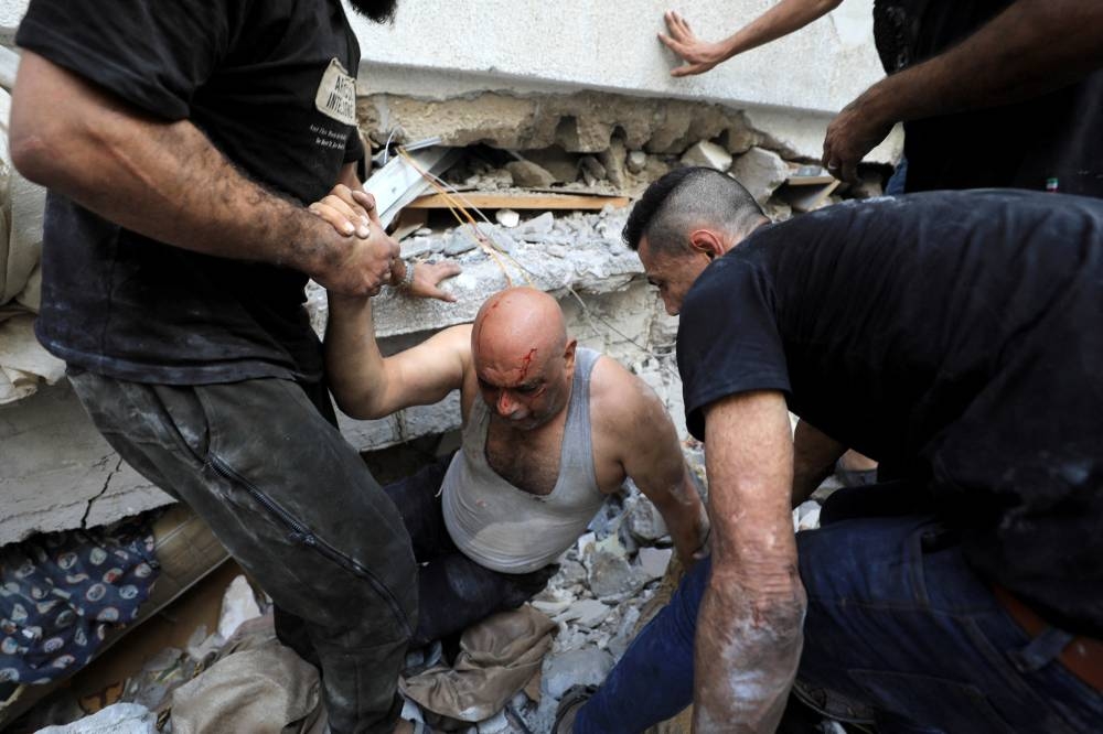 A Palestinian man is assisted at the site of an Israeli strike on a residential building in Gaza City, on Wednesday. REUTERS