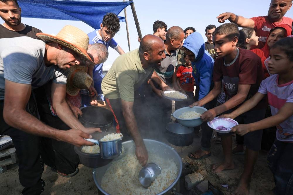 People distribute food at a makeshift camp for displaced people in Khan Yunis in the southern Gaza Strip on Wednesday. AFP