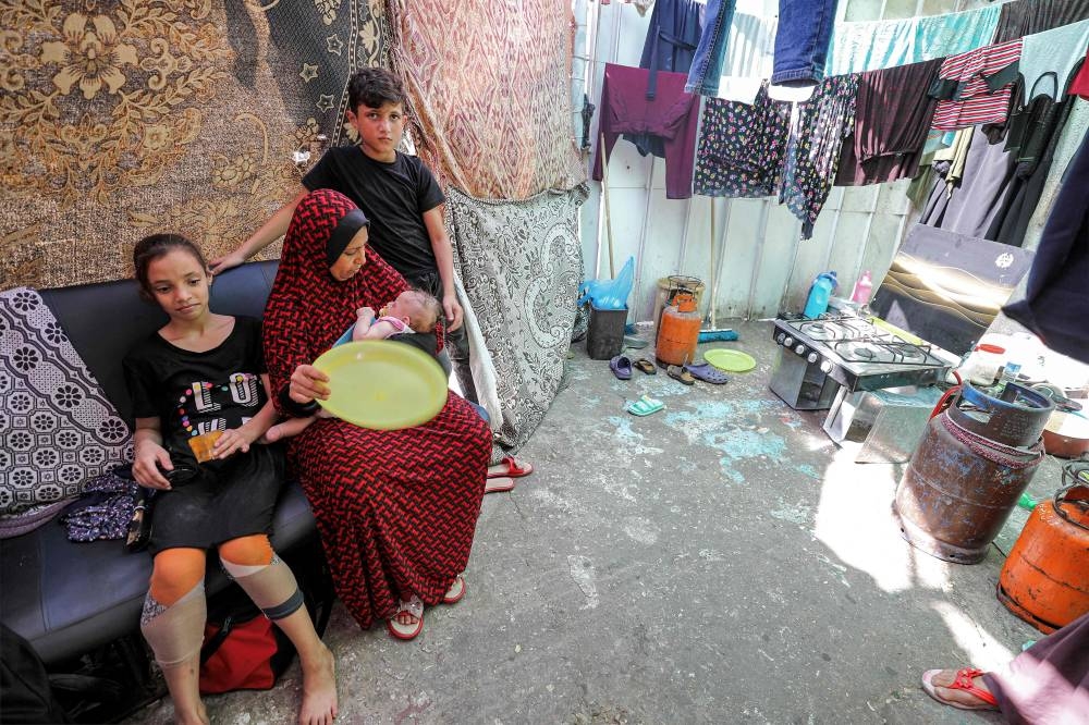 A woman and children from displaced families, who returned from Khan Yunis in the southern Gaza Strip to the north due to the dangers and difficulties they faced there under Israeli bombardment, take shelter at Al-Shifa hospital in Gaza City on Wednesday. AFP