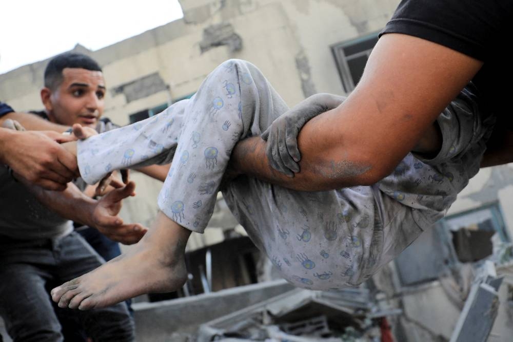 A Palestinian child is assisted as people search for casualties at the site of an Israeli strike on a residential building in Gaza City, on Wednesday. REUTERS