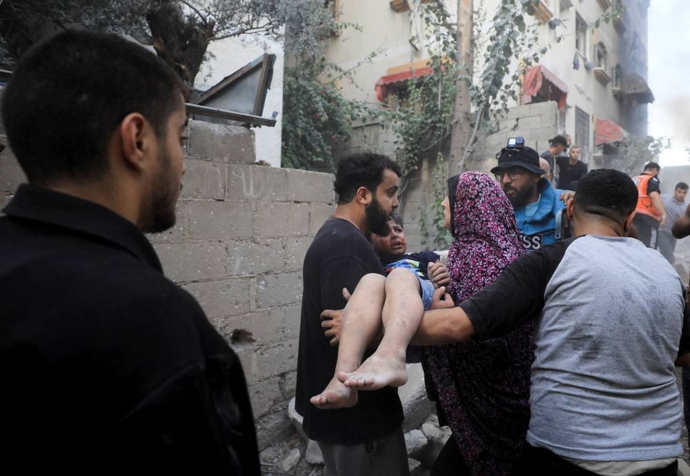 A Palestinian is assisted, at the site of an Israeli strike on a residential building in Gaza City, on Wednesday. REUTERS
