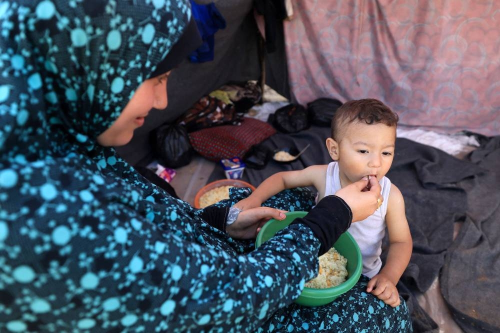 A woman feeds a baby food distributed at a makeshift camp for displaced people in Khan Yunis in the southern Gaza Strip on Wednesday. AFP