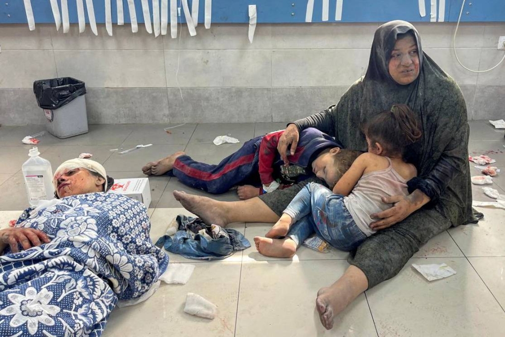 A Palestinian woman holds her children, who were wounded along with her in an Israeli strike, at Shifa hospital in Gaza City, Monday. REUTERS