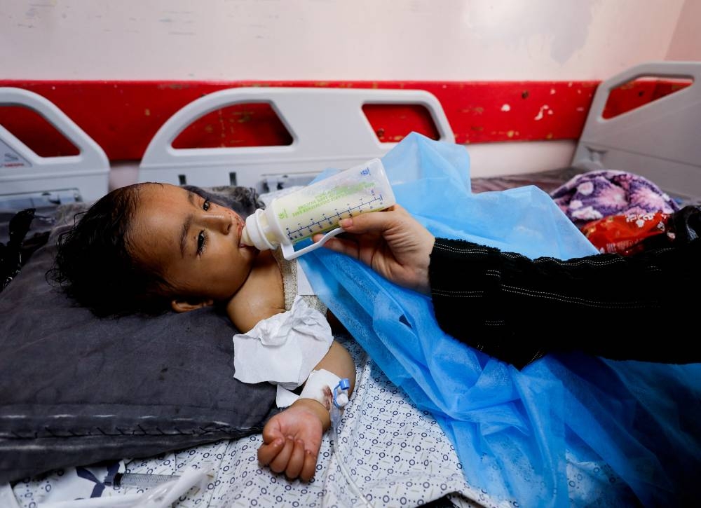 Wateen, a 14 months old Palestinian who was injured in an Israeli strike which killed her mother and injured her twin brother Ahmed, is bottle-fed at Nasser hospital, in Khan Younis, in the southern Gaza Strip, Monday. REUTERS